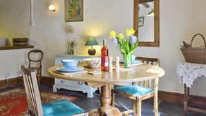 Un coin repas avec une table en bois, des chaises, un vase de fleurs, une lampe et un miroir au mur.