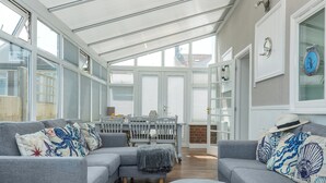 Een zonnige kamer met een grijze modulaire bank, een tafeltje en een verschoningstafel voor baby's.