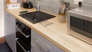 Et moderne køkken med en indbygget ovn, en brødrister og en brødkasse med teksten 