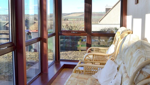 A room with large windows offering a view of a rural landscape. There are wicker chairs with cushions. - 3 bedroom accommodation in Haddington (Haddington)