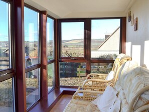 A room with large windows offering a view of a rural landscape. There are wicker chairs with cushions. - 3 bedroom accommodation in Haddington (Haddington)