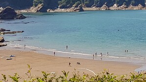A beach with clear water, rocky outcrops, and a forested hillside. - 4 bedroom accommodation in Combe Martin (Combe Martin)