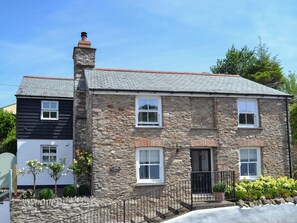 A stone building with a chimney, a gated entrance, and a small porch with a potted plant. - 4 bedroom accommodation in Combe Martin (Combe Martin)