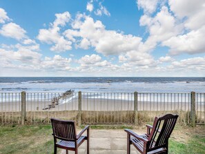 A beach view with a wooden fence, two wooden chairs, and a stone bench. - 3 bedroom accommodation in Bacton (Bacton)