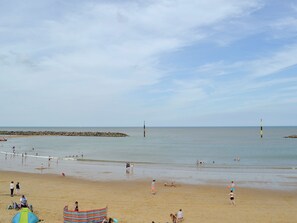 A beach with people, a tent, and a rocky breakwater. - 2 bedroom accommodation in Sea Palling. (Sea Palling.)