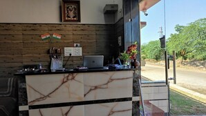 A reception desk with a laptop, calendar, and Indian flags. - Hinglaj Palace Hotel Jawai (Bijapur)