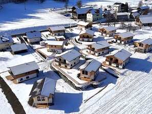 Ein verschneiter Wohnbereich mit mehreren Häusern, einige mit Balkonen und andere mit großen Fenstern.