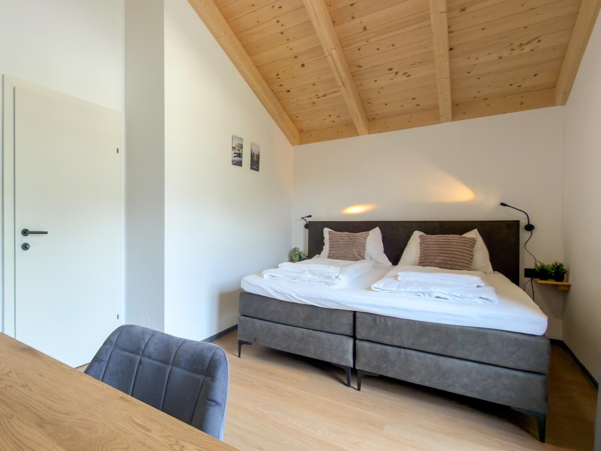 A bedroom with a bed, bedside tables, a desk, and a chair.