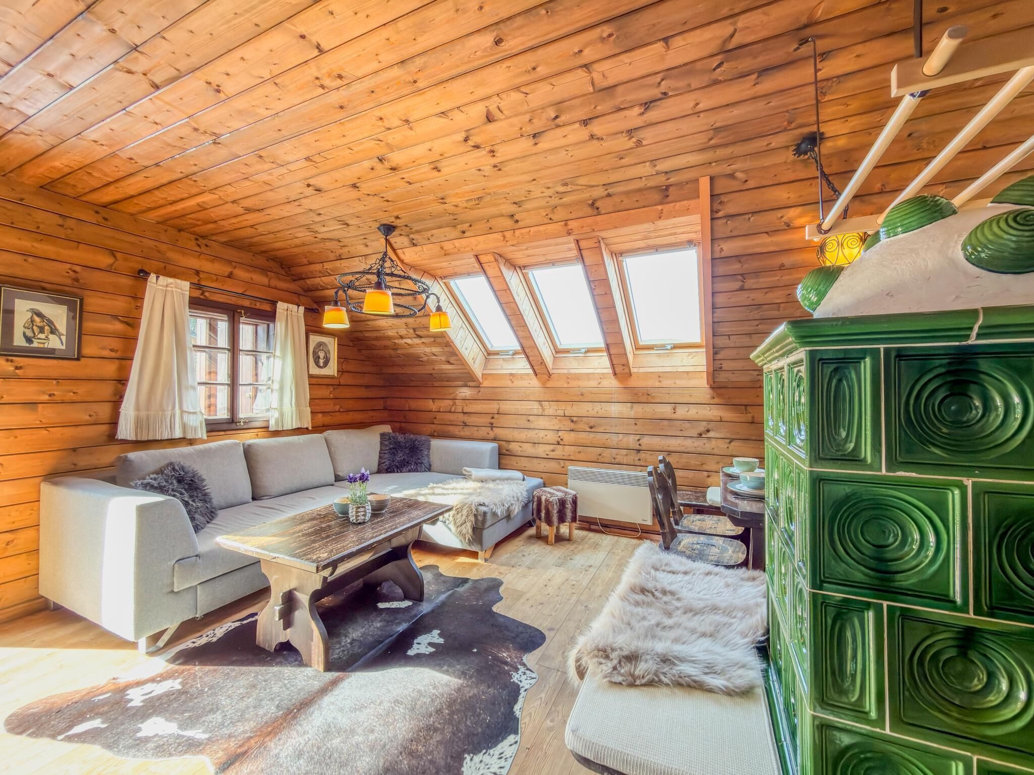 A log cabin interior with a sofa, table, and green cabinet.