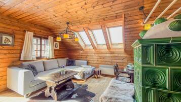 A log cabin interior with a sofa, table, and green cabinet.