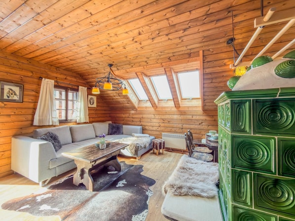 A log cabin interior with a sofa, table, and green cabinet.