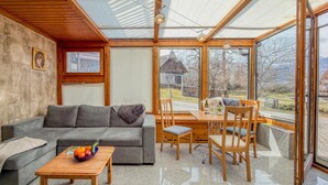 A modern living room with a sofa, dining table, chairs, and a glass ceiling. - Just a few minutes to the Millennium Express (Tröpolach)