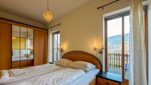 A bedroom with a bed, bedside tables, a mirror, and a balcony with a view. - Just a few minutes to the Millennium Express (Tröpolach)