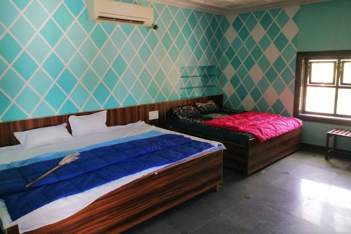 Een slaapkamer met twee bedden, een raam en een wandairconditioner.
