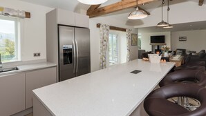 Een moderne keuken met een centraal eiland, roestvrijstalen apparatuur, hangende lampen en een eetgedeelte met lederen stoelen.