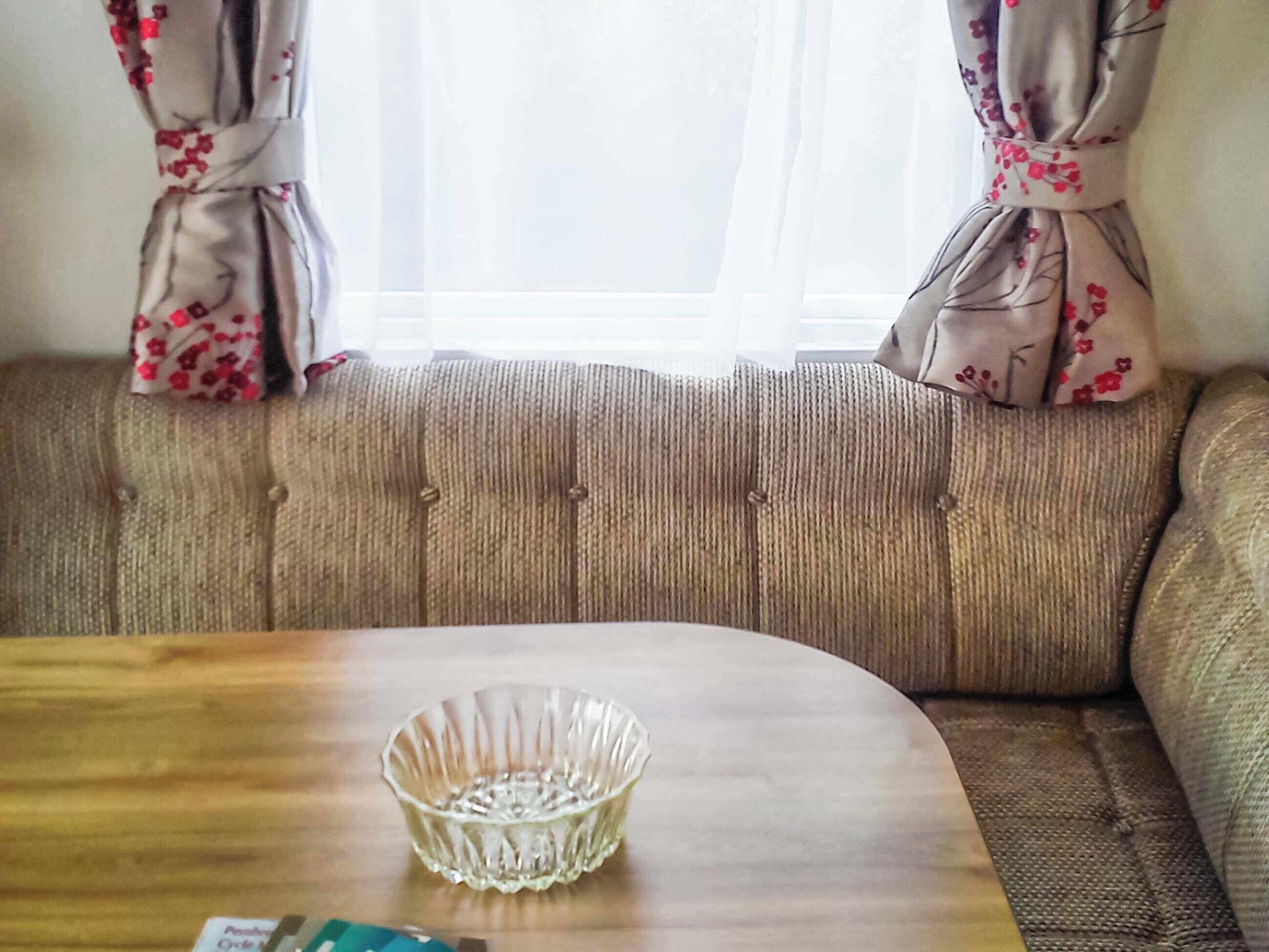 A room with a sofa and a wooden table with a glass bowl.