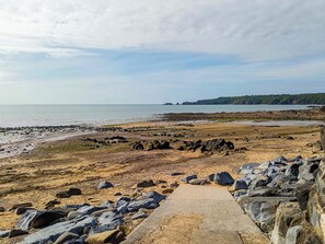 Ein felsiger Strand mit einem Betonweg zum Wasser.