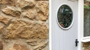 A stone wall, a white door with a glass window, and a door handle. - 2 bedroom accommodation in Staithes, near Whitby (Staithes, near Whitby)