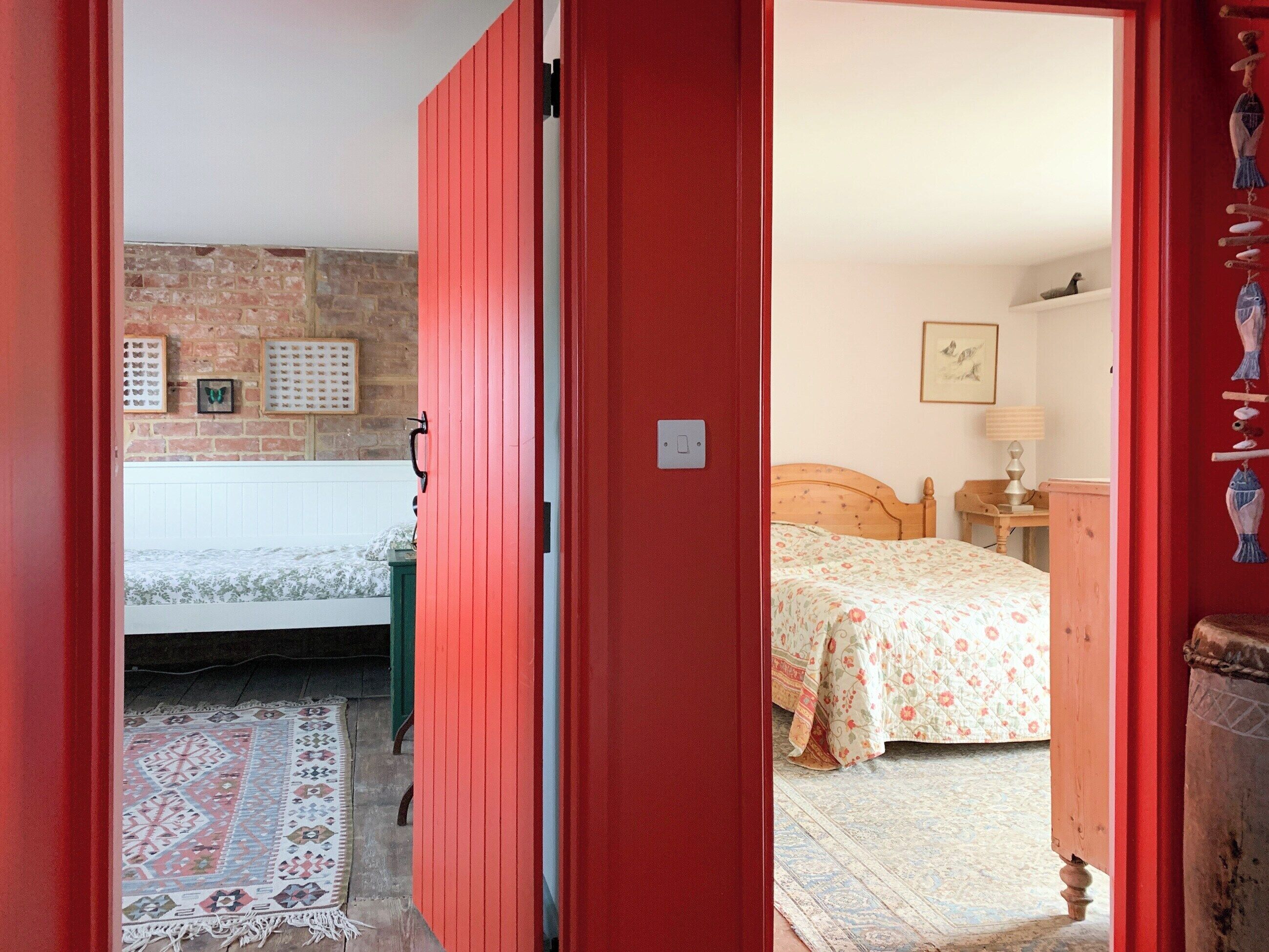 Een kamer met een bed, een nachtkastje, een lamp en een muur met ingekaderde foto's.