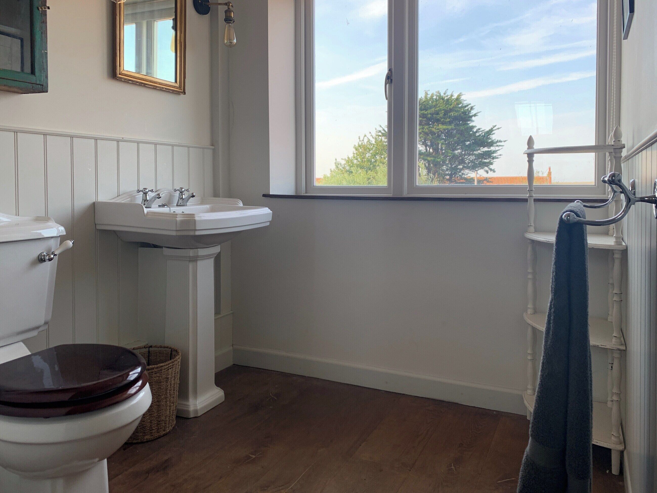 A bathroom with a toilet, sink, and window.