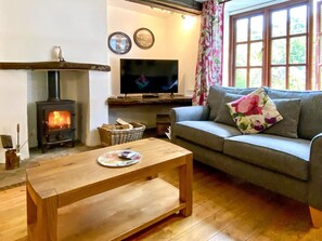 Ein gemütliches Wohnzimmer mit Kamin, einer Couch, einem Fernseher und einem Holztisch.