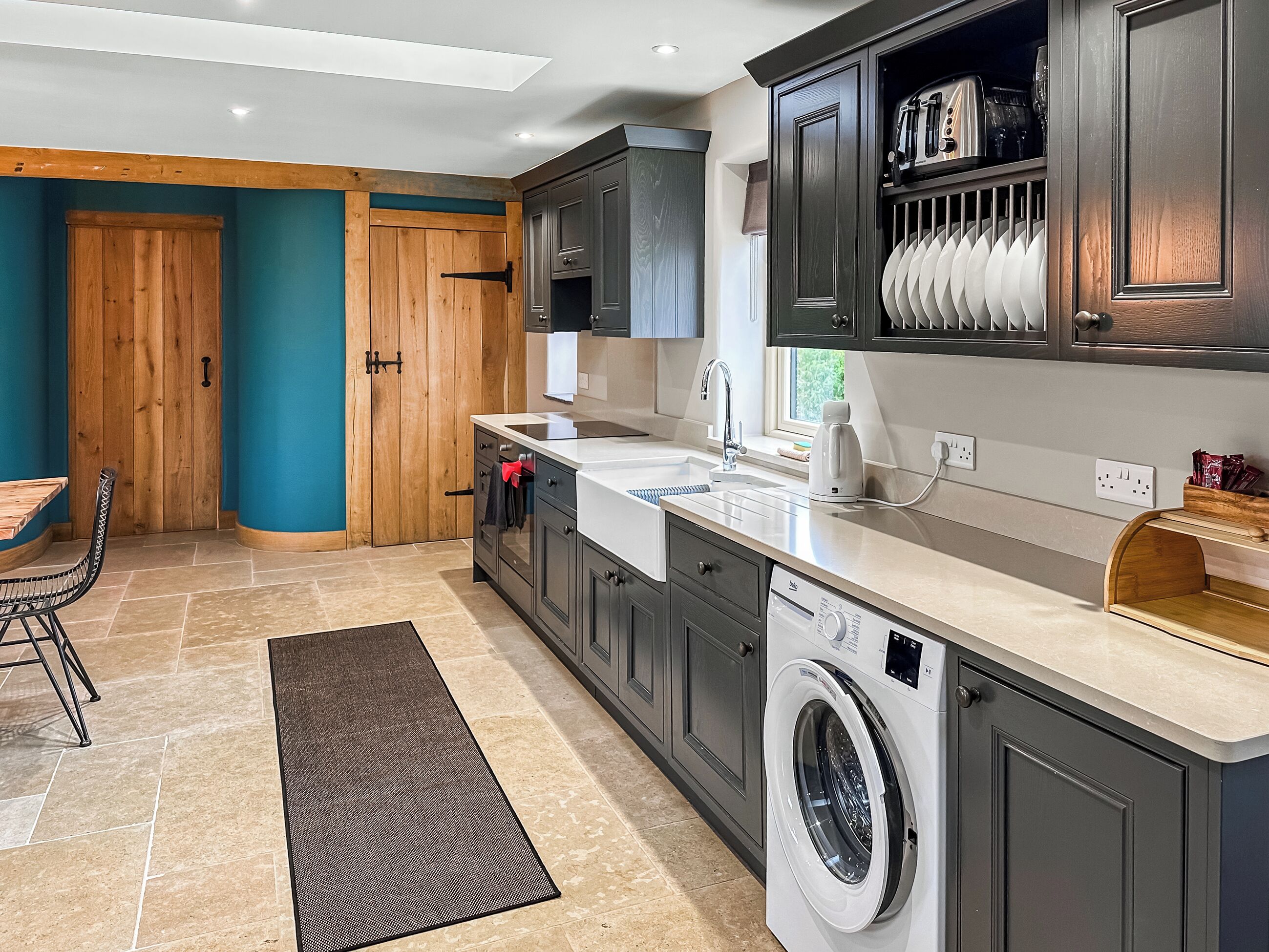 A modern kitchen with a built-in washing machine, a dining area with a table and chairs, and a wooden door.