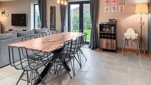 Et moderne opholdsrum med spiseplads, sofa, fjernsyn og kunstværker.