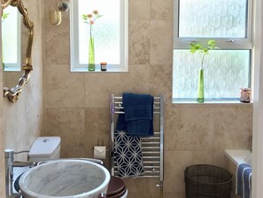 A bathroom with a marble sink, a toilet, a towel rack with a blue towel, a decorative mirror, and two windows with plants. - 4 bedroom accommodation in Fowey (Fowey)
