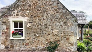 Un edificio de piedra con una ventana pequeña y una caja de flores.