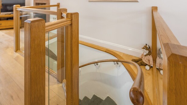 Un escalier en bois avec des rampes en verre et une main courante.