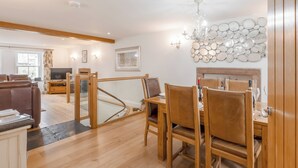 Un vaste espace de vie comprenant une table à manger en bois, des sièges confortables, un téléviseur et un escalier menant à un autre niveau.