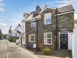 A stone-built cottage with a black front door, white windows, and a visible sign reading "Tommy's Cottage." - 3 bedroom accommodation in Keswick (Keswick)