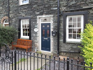 A stone building with a blue door, a bench outside, and a black metal fence. - 2 bedroom accommodation in Keswick (Keswick)