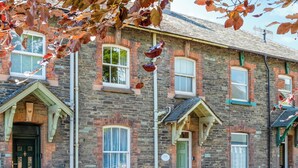 A stone building with multiple windows and doors, including a green door and a white-framed window. - 3 bedroom accommodation in Keswick (Keswick)