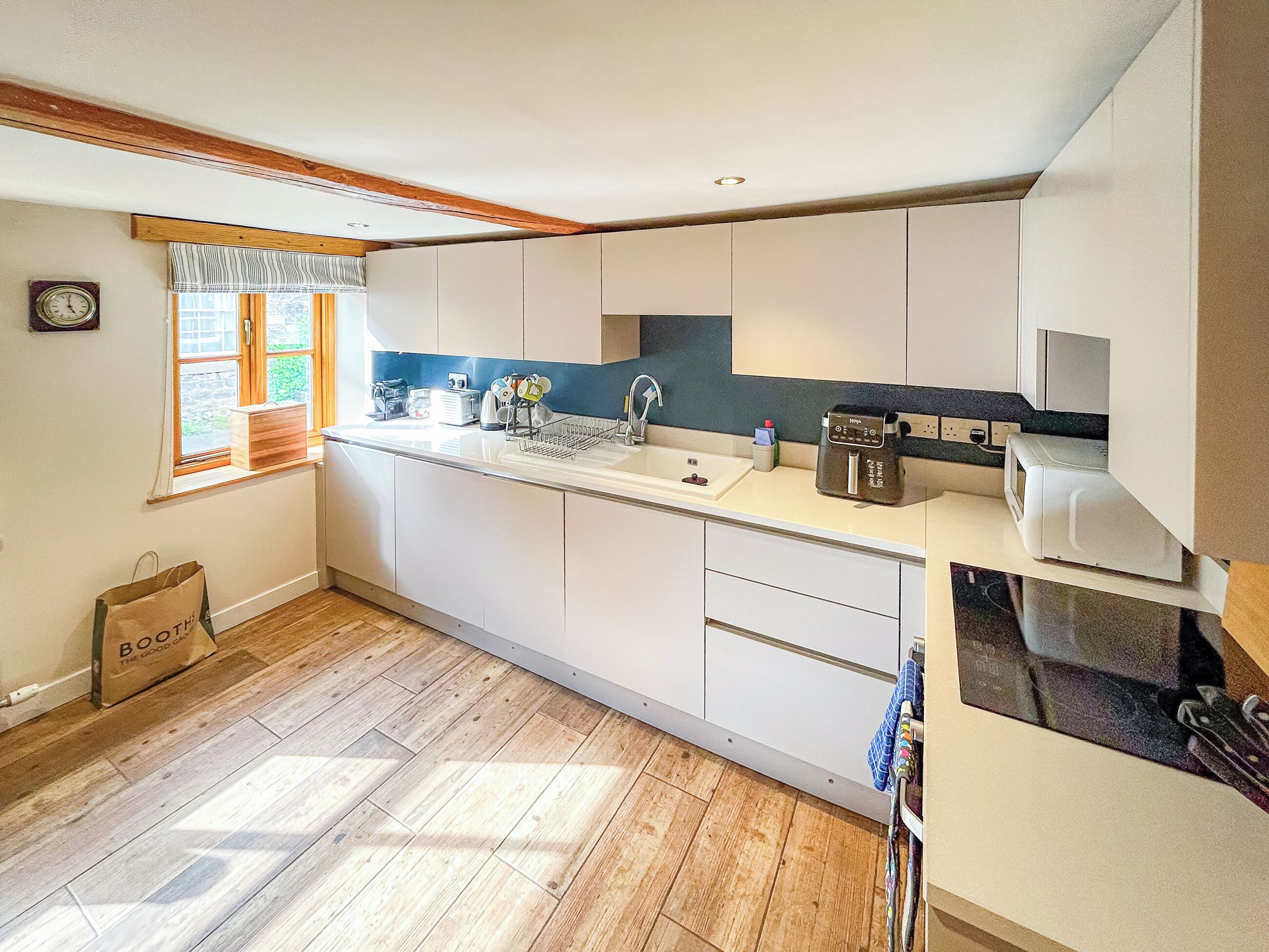 A modern kitchen with white cabinets, a wooden countertop, a sink, and a window with curtains.