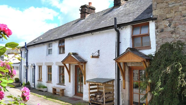 A traditional white building with a stone facade, wooden porch, and a bench outside. - 2 bedroom accommodation in Pooley Bridge (Pooley Bridge)