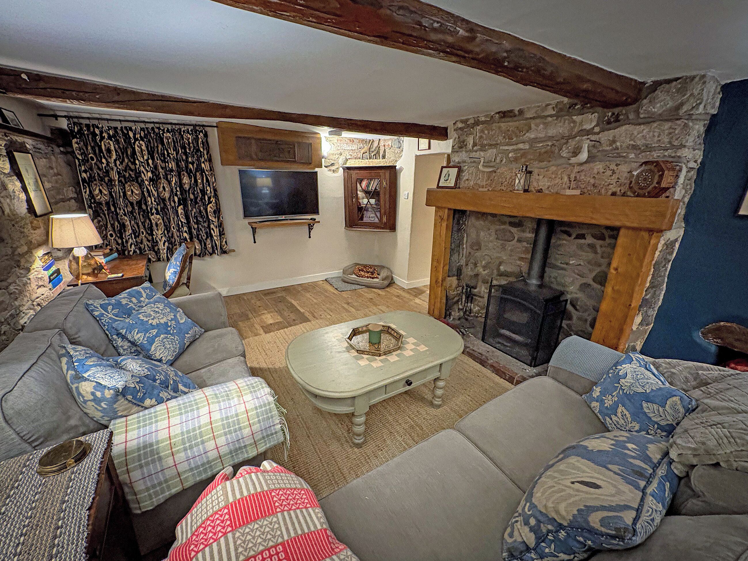 A cozy living room with a stone fireplace, a television, and a sofa set.