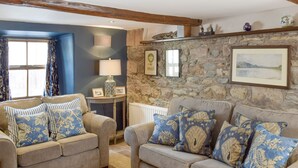 A cozy living room with two sofas, a stone wall, and a wooden ceiling beam. - 2 bedroom accommodation in Pooley Bridge (Pooley Bridge)