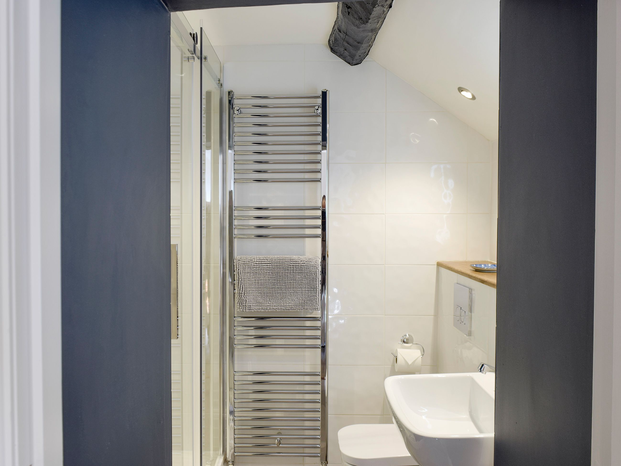 Uma casa de banho moderna com cabine de duche em vidro, lavatório branco e sanita.