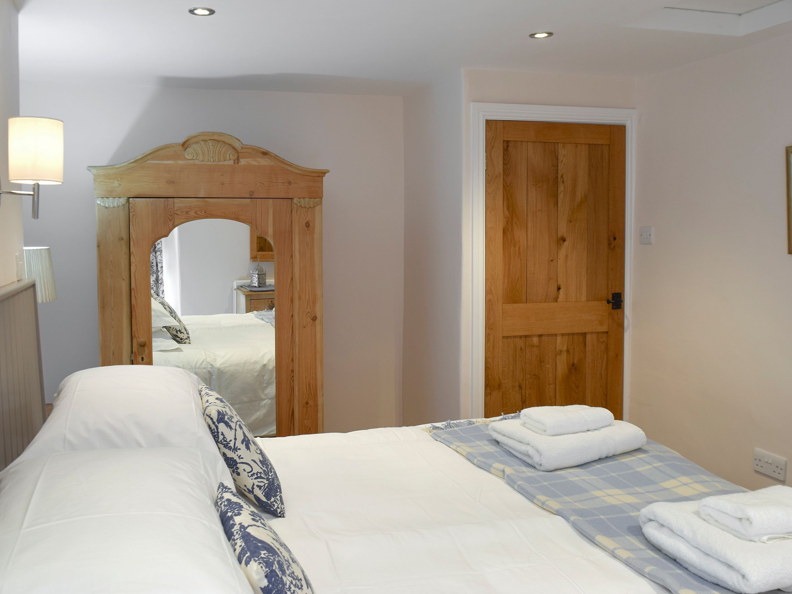 A bedroom with a bed, a wooden door, and a mirror.