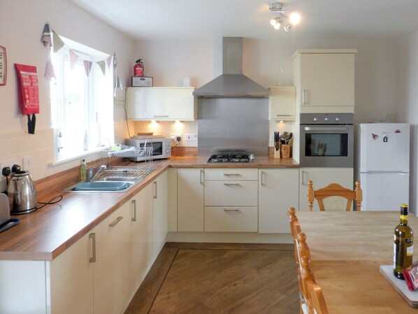 A compact kitchen with a gas stove, microwave, oven, and refrigerator. - 3 bedroom accommodation in Beadnell (Beadnell)