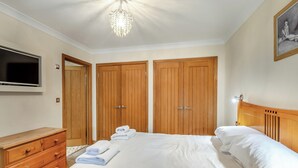 A bedroom with a bed, wooden wardrobe, a dresser, a television, and a chandelier. - 1 bedroom accommodation in Red Row near Amble (Red Row near Amble)