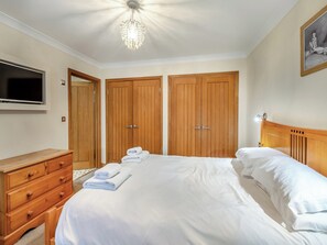 Ein Schlafzimmer mit einem Bett, einem Holzschrank, einem Schminktisch, einem Fernseher und einer Chandelier.