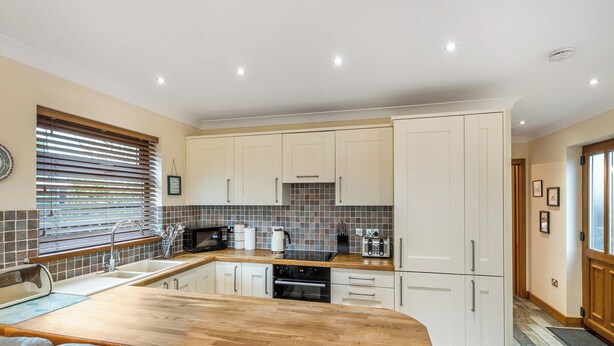 A modern kitchen with white cabinets, a wooden countertop, and a built-in oven. - 1 bedroom accommodation in Red Row near Amble (Red Row near Amble)