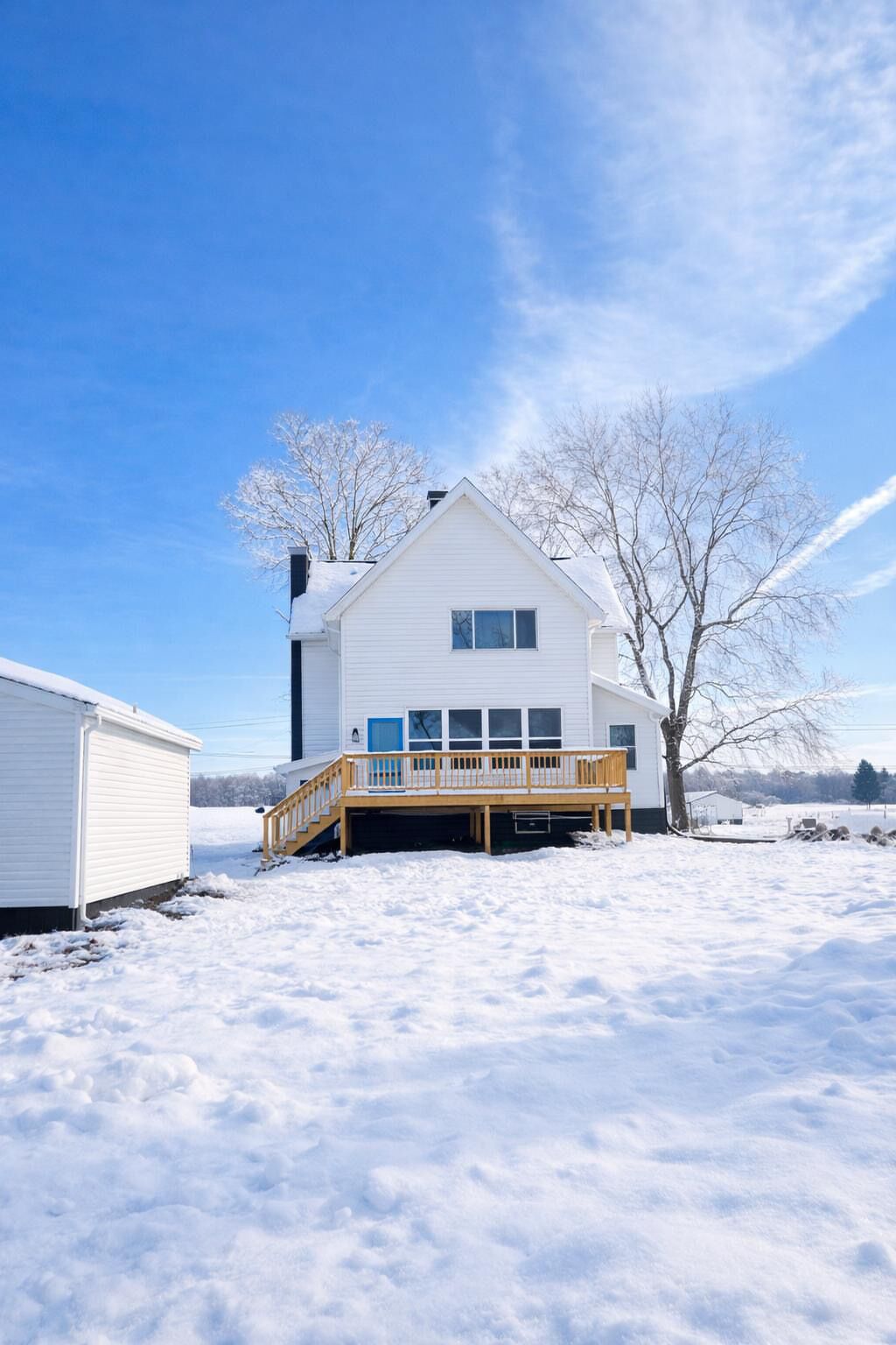 A white single-story house with a wooden deck and a small porch.