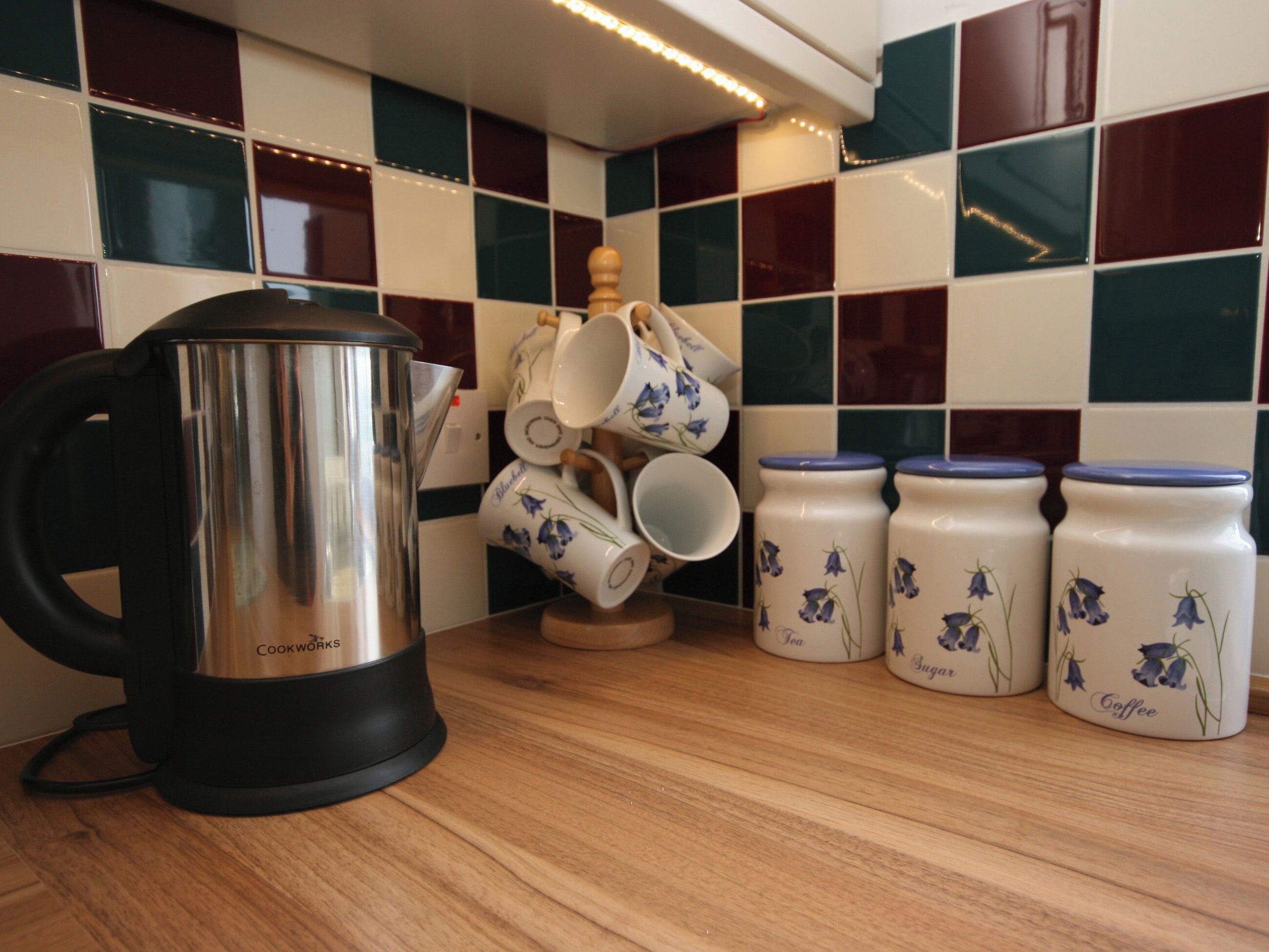 Eine Küchenarbeitsplatte mit einer Kaffeemaschine, gestapelten Tassen sowie Zucker- und Kaffeebelikken.