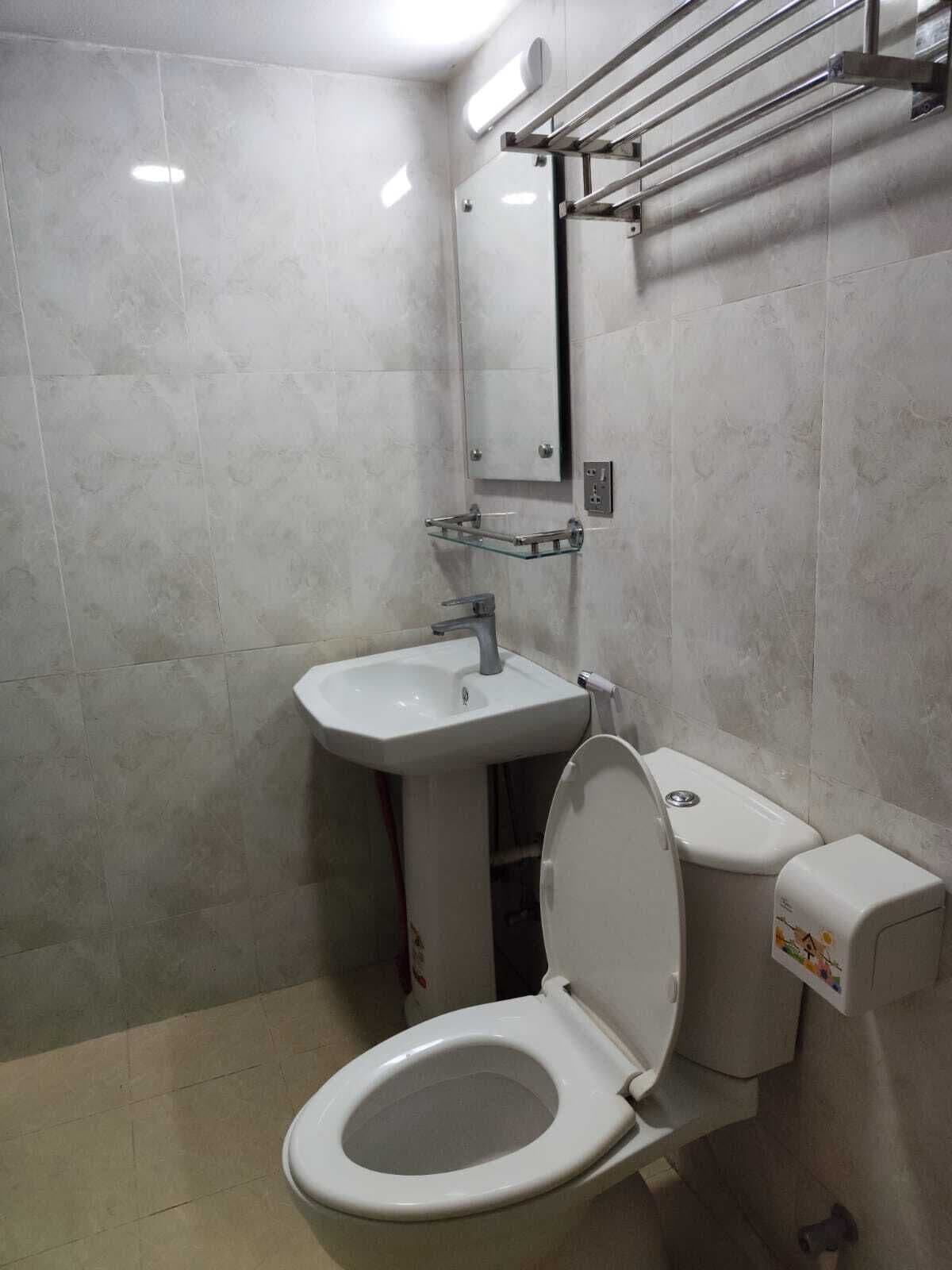 A bathroom with a toilet, sink, and a towel rack.