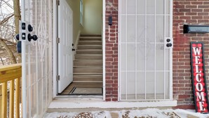 Une entrée de maison avec une pancarte de bienvenue, une boîte aux lettres et une porte donnant sur un escalier.