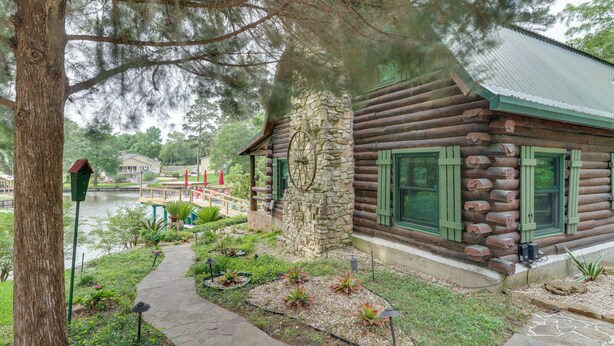 A log cabin with a stone chimney, a stone wall, and a view of a lake. - Private Hot Tub & Dock! Lakefront Log Cabin Oasis (Onalaska)