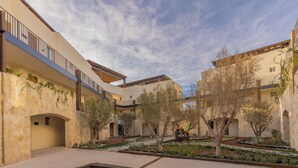 A courtyard with stone walls, trees, and a fire pit. - Hotel Santolivo by Lumina (Parras de la Fuente)